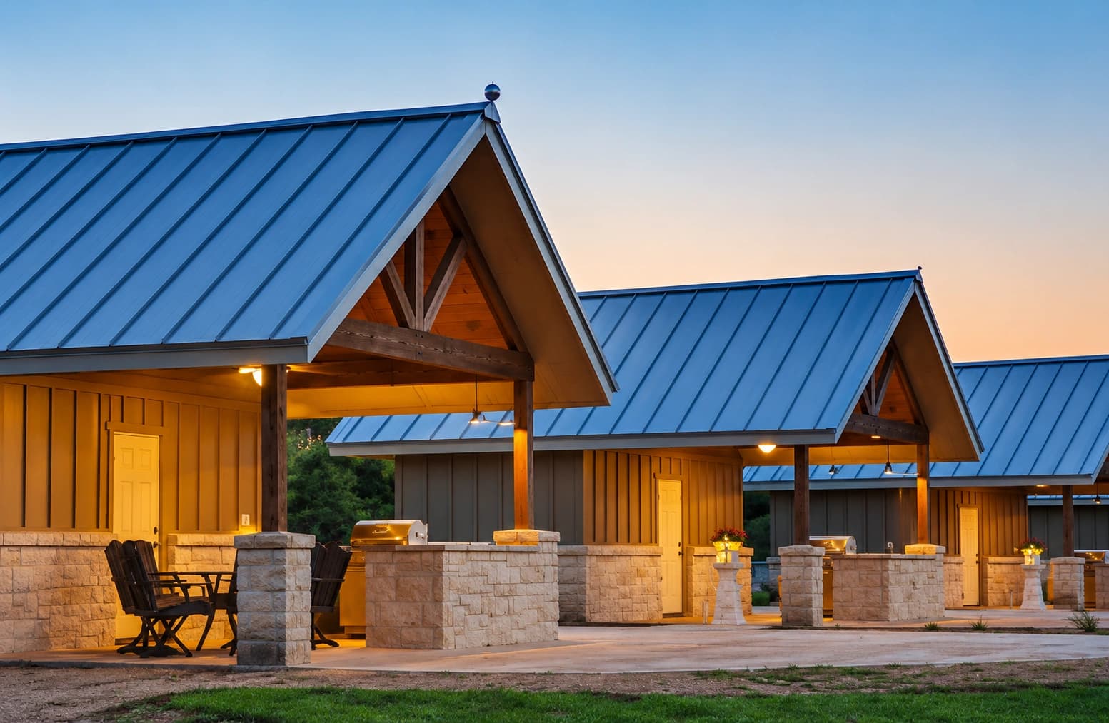 Casitas at dusk with stone bases, timber trusses and standing-seam roofs.