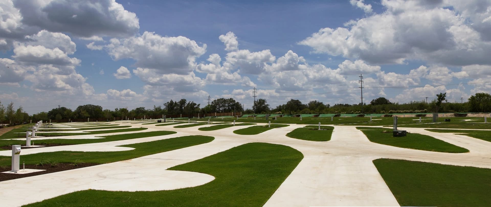 Spacious pull-through RV site with concrete pad and manicured lawn